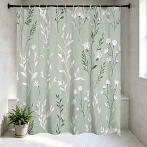 May include: A sage green shower curtain featuring a repeating pattern of white and dark green floral and botanical designs. The curtain is hanging in a bathroom with a potted fern.