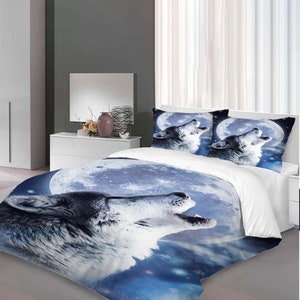 Puede incluir: Un juego de cama blanco y azul con un lobo aullando a la luna. El lobo es gris y blanco y la luna es azul con estrellas blancas. El juego de cama incluye una funda nórdica y dos fundas de almohada.