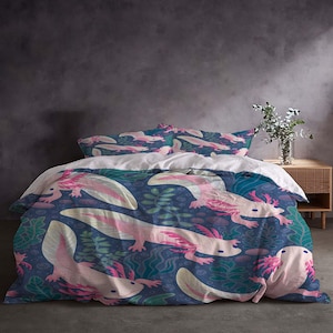 Op de afbeelding: Een beddengoedset met een herhalend patroon van roze en witte axolotls op een donkerblauwe achtergrond. Het ontwerp bevat waterplanten in groen- en blauwtinten. De set bevat een dekbedovertrek en kussenslopen.