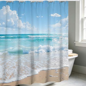 May include: A shower curtain featuring a beach scene with a blue sky, white clouds, and turquoise water. The curtain depicts waves breaking on a sandy shore, creating a serene and coastal atmosphere. The design evokes a sense of relaxation and the ocean.