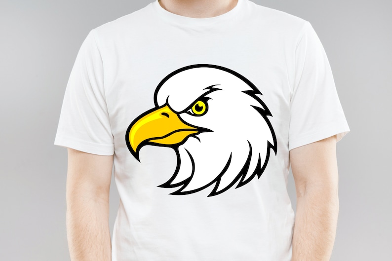 May include: White t-shirt with a black and yellow cartoon eagle head graphic.