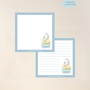 May include: Printable stationery featuring a grey and white cat sitting on a stack of colourful books. The stationery has a blue border and the text "tanjacreativestudio.etsy.com" at the bottom.