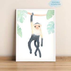 May include: Watercolor print of a monkey hanging from a branch, surrounded by green leaves. The monkey has a white face and a gray body. The words "PRINTABLE DOWNLOAD" are in the upper right corner. The artwork is framed in a white border.