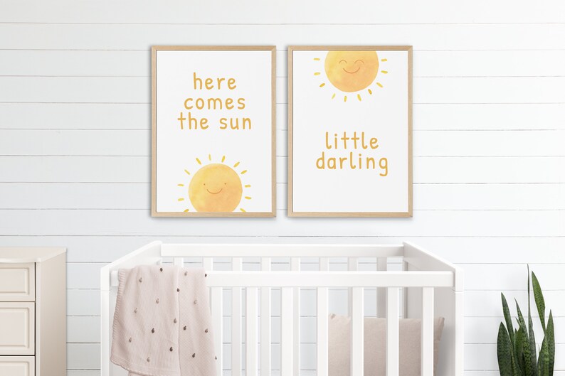 May include: Two framed prints with a yellow sun and text. The left print says "here comes the sun" and the right print says "little darling".