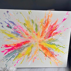 May include: Abstract canvas art featuring a vibrant explosion of color. The artwork showcases a burst of neon pink, orange, yellow, green, and purple paint splatters against a neutral background. A modern and colorful piece.