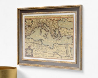 May include: Framed vintage map of the Mediterranean Sea, featuring detailed cartography with text in English. The map is encased in a gold-toned wooden frame with a dark gray matting, creating a classic aesthetic. The map's colors are muted, with a sepia tone.