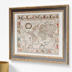 May include: Framed antique world map print. The map features detailed illustrations and text, with a focus on the continents and oceans. The frame is gold with a grey mount, adding a classic touch to the artwork. The print is a vintage style.