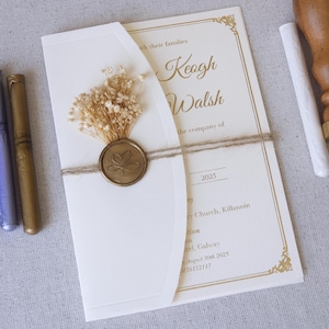 May include: Cream wedding invitation with gold calligraphy and floral details. The invitation is sealed with a gold wax seal and tied with twine. The text reads "Keogh Walsh" and "August 30th 2025".
