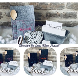 Puede incluir: Tres bolsas de fieltro gris con una cuchara de madera y un adorno de metal en forma de corazón. Cada bolsa tiene un diseño de estrella y el texto "Auszeit" bordado en ella. Las bolsas se muestran en una superficie blanca con un letrero blanco que dice "Tazeeline".