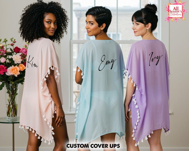 Op de afbeelding: Drie transparante cover-ups in pastelkleuren: lichtroze, lichtblauw en lavendel. Elke cover-up heeft witte kwastjes en een naam op de rug. De tekst "CUSTOM COVER UPS" staat onderaan de afbeelding. Het logo "All Season's Celebrations" staat rechtsboven.