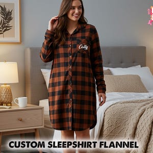 May include: A long-sleeved, button-down sleepshirt in a brown and black plaid pattern. The sleepshirt has a personalized name embroidered on the chest. The image also features a nightstand with a lamp, a framed picture, and the text "CUSTOM SLEEPSHIRT FLANNEL".