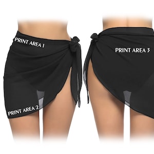 May include: Two black sarongs, each tied at the waist. The fabric drapes to create a skirt-like appearance. The text "PRINT AREA 1", "PRINT AREA 2", and "PRINT AREA 3" are visible on the fabric. The sarongs are made of a lightweight, sheer material.