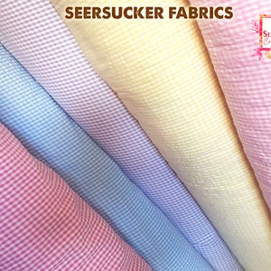 May include: Close-up of seersucker fabrics in various colors, including pink, blue, yellow, and purple. The fabrics have a textured, puckered appearance with a checkered pattern. The text "SEERSUCKER FABRICS" is visible at the top.