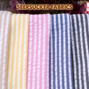 May include: Close-up of seersucker fabrics in various colors, including beige, yellow, pink, blue, and gray, each with white vertical stripes. The text "SEERSUCKER FABRICS" is displayed at the top of the image.