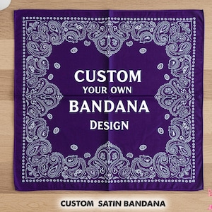 May include: A square, deep purple bandana with a white paisley pattern around the edges. The centre of the bandana features the text "CUSTOM YOUR OWN BANDANA DESIGN" in white. The words "CUSTOM SATIN BANDANA" are at the bottom.