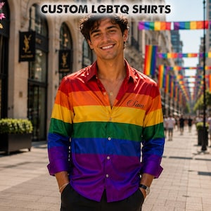 May include: A long-sleeved button-down shirt featuring horizontal rainbow stripes in red, orange, yellow, green, blue, and purple. The shirt has a collar, a front button placket, and the name Sam embroidered in black script on the left chest.