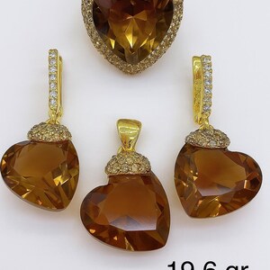 Puede incluir: Un conjunto de joyas con un colgante, pendientes y un anillo en forma de corazón. Las piezas tienen un engaste de oro y están adornadas con piedras preciosas facetadas de color ámbar. El peso total es de 19,6 gramos.