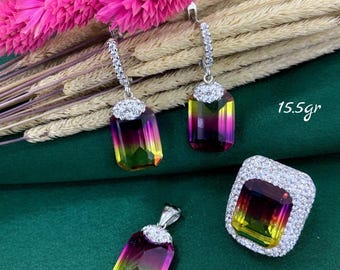 Puede incluir: Un conjunto de joyas de plata con un colgante, pendientes y anillo de piedra preciosa de color arcoíris. El conjunto está decorado con pequeñas piedras de circonita cúbica transparentes. El conjunto pesa 15,5 gramos.