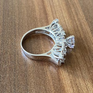 May include: A silver ring with a large, clear center stone and smaller stones set in a delicate, intricate design.