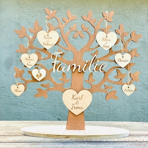 Könnte beinhalten: Ein Familienbaum aus Holz mit herzförmigen Ornamenten. Die Ornamente sind mit Namen und dem Wort "Familie" graviert.