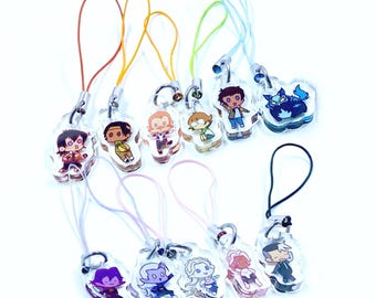May include: A collection of clear acrylic charms featuring colorful cartoon character designs. Each charm has a different character, with a matching colored lanyard attached. The charms are on a white background.
