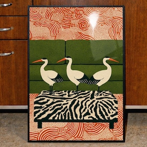 Puede incluir: Impresión artística enmarcada que presenta tres aves blancas con picos naranjas sobre un banco con estampado de cebra. El fondo tiene un diseño de bloques verdes y un patrón naranja y blanco. La obra de arte se exhibe en un entorno de cocina retro.