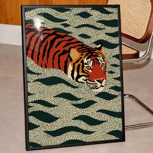 Stylized tiger illustration moving through abstract green wave patterns with dotted textures on a neutral background. The bold orange and black striped tiger contrasts with the rhythmic organic shapes, creating a dynamic maximalist composition. Hand drawn details and modern folk art influences give the artwork a playful yet powerful visual identity. Perfect for living room wall decor, kids room styling, eclectic interiors, or jungle themed spaces seeking a bold statement animal artwork.