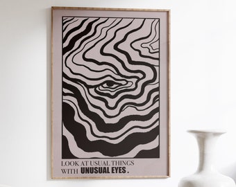 May include: Black and white abstract art print with a single eye in the center. The print is framed and has the text "LOOK AT USUAL THINGS WITH UNUSUAL EYES."