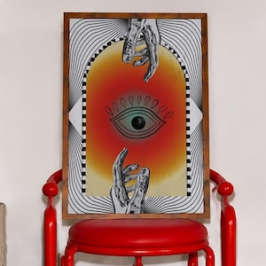 May include: A rectangular framed wall art piece featuring a central graphic of a stylized eye within a red and orange gradient archway, flanked by black and white wavy lines, with two detailed monochrome hands reaching toward the eye from above and below.