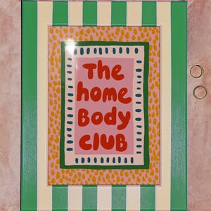 Playful typography poster featuring the phrase The Home Body Club in bold red lettering on a soft pink background. Framed with green and cream borders and surrounded by mustard yellow abstract dots, this colorful maximalist design blends cozy lifestyle humor with eclectic pattern layering and retro-inspired charm.Home Body Poster, Typography Wall Art, Cozy Quote Print, Maximalist Decor, Eclectic Print, Retro Style Poster, Entryway Wall Decor, Bold Letter Art, Trendy Art Print, Dopamine Color Art