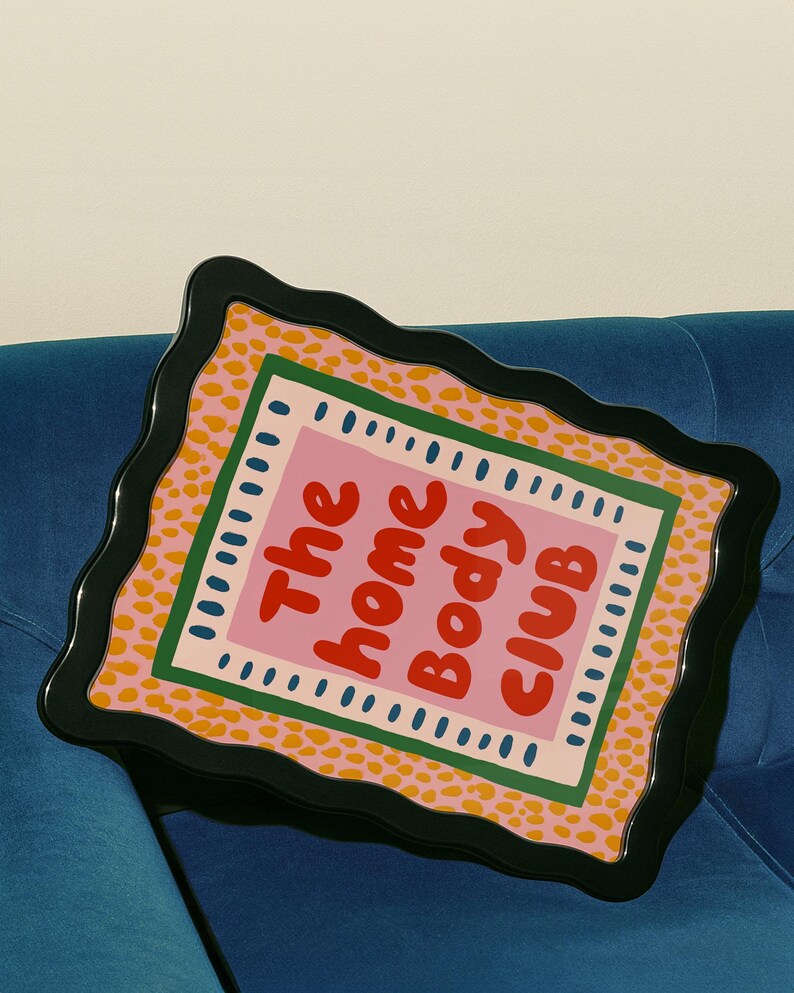 Playful typography poster featuring the phrase The Home Body Club in bold red lettering on a soft pink background. Framed with green and cream borders and surrounded by mustard yellow abstract dots, this colorful maximalist design blends cozy lifestyle humor with eclectic pattern layering and retro-inspired charm.Home Body Poster, Typography Wall Art, Cozy Quote Print, Maximalist Decor, Eclectic Print, Retro Style Poster, Entryway Wall Decor, Bold Letter Art, Trendy Art Print, Dopamine Color Art