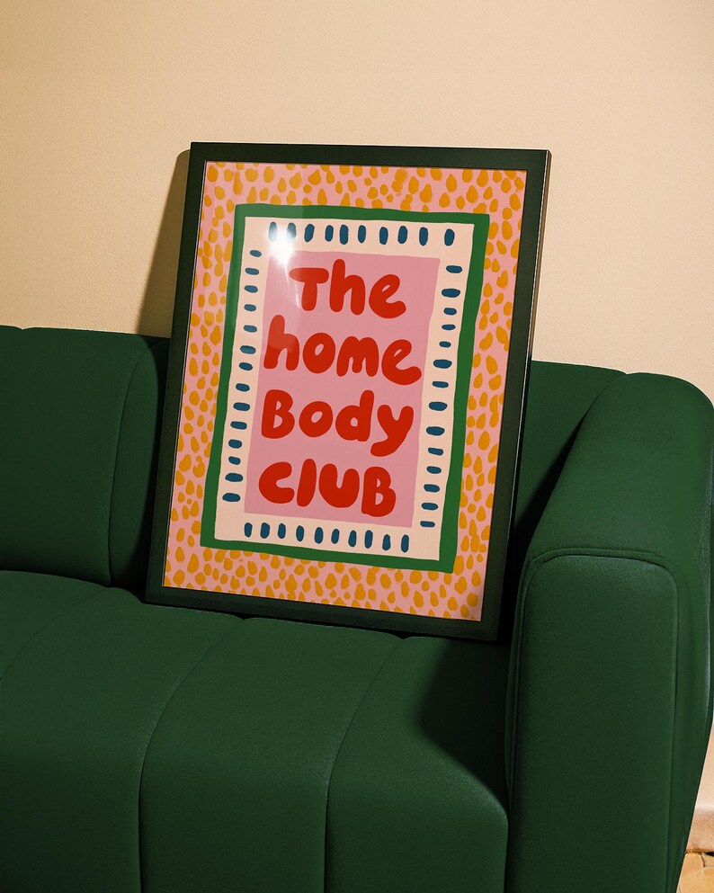 Playful typography poster featuring the phrase The Home Body Club in bold red lettering on a soft pink background. Framed with green and cream borders and surrounded by mustard yellow abstract dots, this colorful maximalist design blends cozy lifestyle humor with eclectic pattern layering and retro-inspired charm.Home Body Poster, Typography Wall Art, Cozy Quote Print, Maximalist Decor, Eclectic Print, Retro Style Poster, Entryway Wall Decor, Bold Letter Art, Trendy Art Print, Dopamine Color Art