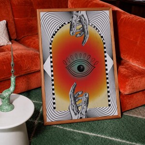 May include: A framed rectangular wall art print featuring a central archway with a gradient orange and yellow background. Inside the arch is a black line drawing of an eye, positioned between two reaching hands. The border has black and white lines.