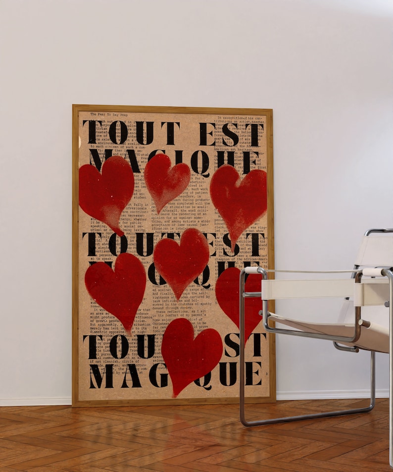 May include: A framed print with the text "Tout Est Magique" repeated three times in black letters. The background is a vintage newspaper print with red hearts painted over the text.