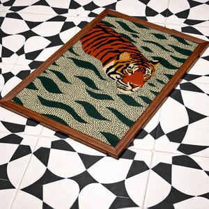Stylized tiger illustration moving through abstract green wave patterns with dotted textures on a neutral background. The bold orange and black striped tiger contrasts with the rhythmic organic shapes, creating a dynamic maximalist composition. Hand drawn details and modern folk art influences give the artwork a playful yet powerful visual identity. Perfect for living room wall decor, kids room styling, eclectic interiors, or jungle themed spaces seeking a bold statement animal artwork.