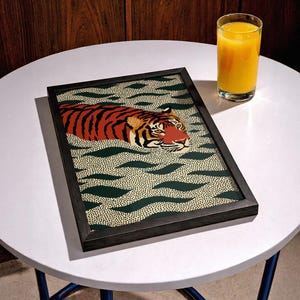 Stylized tiger illustration moving through abstract green wave patterns with dotted textures on a neutral background. The bold orange and black striped tiger contrasts with the rhythmic organic shapes, creating a dynamic maximalist composition. Hand drawn details and modern folk art influences give the artwork a playful yet powerful visual identity. Perfect for living room wall decor, kids room styling, eclectic interiors, or jungle themed spaces seeking a bold statement animal artwork.