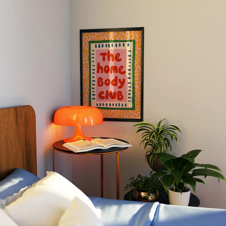 Playful typography poster featuring the phrase The Home Body Club in bold red lettering on a soft pink background. Framed with green and cream borders and surrounded by mustard yellow abstract dots, this colorful maximalist design blends cozy lifestyle humor with eclectic pattern layering and retro-inspired charm.Home Body Poster, Typography Wall Art, Cozy Quote Print, Maximalist Decor, Eclectic Print, Retro Style Poster, Entryway Wall Decor, Bold Letter Art, Trendy Art Print, Dopamine Color Art