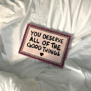 A heartwarming affirmation poster featuring the phrase You Deserve All Of The Good Things in hand-lettered black text with a pink and cream border. Perfect for self-love decor, home offices, or as a thoughtful gift. This piece adds positivity, encouragement, and warmth to any wall.You Deserve Poster, Self Love Wall Art, Positive Quote Print, Motivational Home Art, Pink Modern Poster, Inspirational Typography, Empowering Print, Daily Affirmation Art, Encouraging Quote, Feminine Room Print
