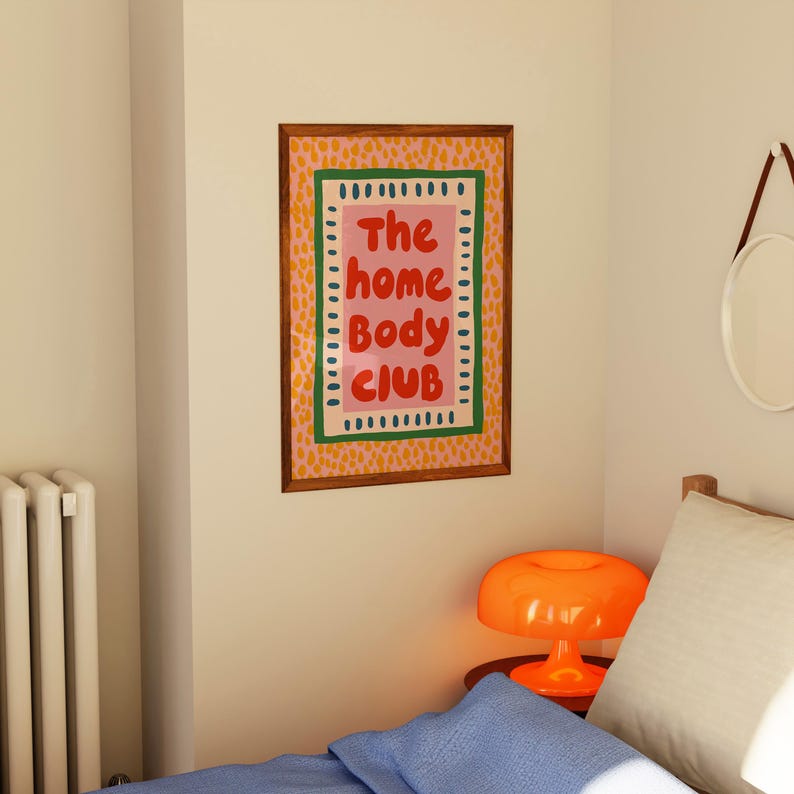 Playful typography poster featuring the phrase The Home Body Club in bold red lettering on a soft pink background. Framed with green and cream borders and surrounded by mustard yellow abstract dots, this colorful maximalist design blends cozy lifestyle humor with eclectic pattern layering and retro-inspired charm.Home Body Poster, Typography Wall Art, Cozy Quote Print, Maximalist Decor, Eclectic Print, Retro Style Poster, Entryway Wall Decor, Bold Letter Art, Trendy Art Print, Dopamine Color Art