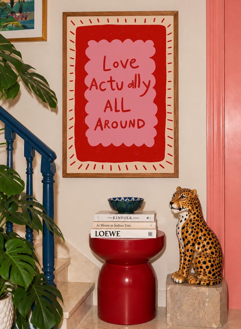 A playful pink and red typography print featuring the hand-lettered message “Love Actually All Around” inside a scalloped frame. The warm peach background, bold lettering and imperfect drawn texture give the artwork a cheerful, handmade character. Designed for bedrooms, living rooms, gallery walls or an above-bed display, this romantic wall art adds color without feeling overly formal. A thoughtful choice for anniversaries, Valentine’s Day, newlyweds or anyone who loves expressive quote posters.