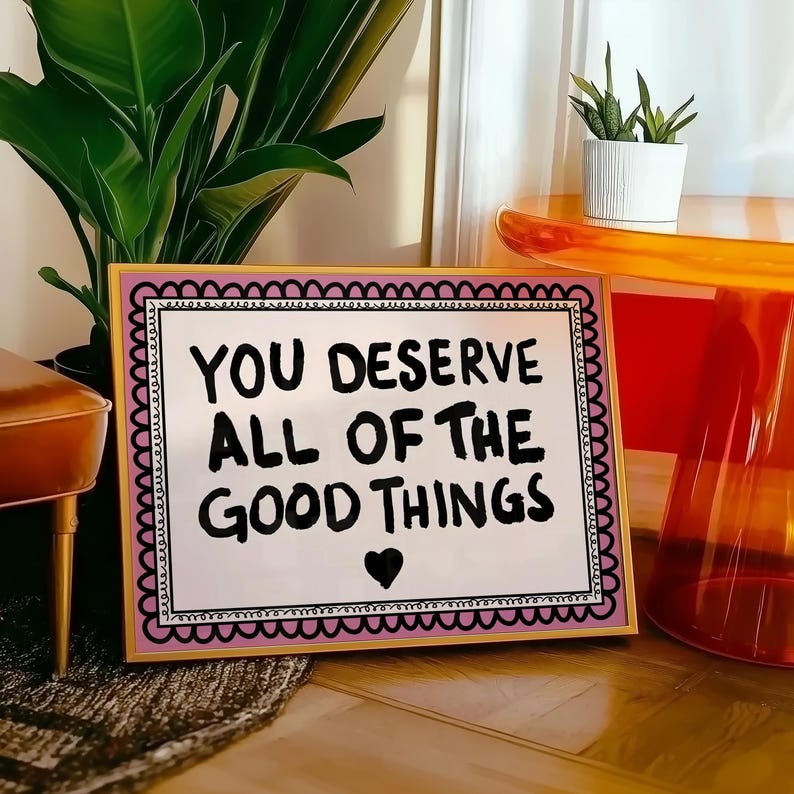Puede incluir: Un letrero enmarcado con el mensaje "YOU DESERVE ALL OF THE GOOD THINGS" en letras negras, un coraz&oacute;n negro y un borde festoneado rosa y negro. El marco es dorado.