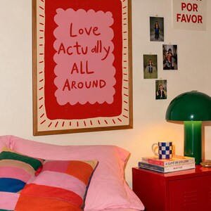 A playful pink and red typography print featuring the hand-lettered message “Love Actually All Around” inside a scalloped frame. The warm peach background, bold lettering and imperfect drawn texture give the artwork a cheerful, handmade character. Designed for bedrooms, living rooms, gallery walls or an above-bed display, this romantic wall art adds color without feeling overly formal. A thoughtful choice for anniversaries, Valentine’s Day, newlyweds or anyone who loves expressive quote posters.