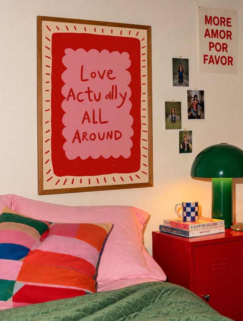 A playful pink and red typography print featuring the hand-lettered message “Love Actually All Around” inside a scalloped frame. The warm peach background, bold lettering and imperfect drawn texture give the artwork a cheerful, handmade character. Designed for bedrooms, living rooms, gallery walls or an above-bed display, this romantic wall art adds color without feeling overly formal. A thoughtful choice for anniversaries, Valentine’s Day, newlyweds or anyone who loves expressive quote posters.