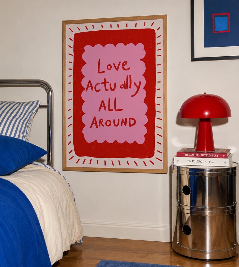 A playful pink and red typography print featuring the hand-lettered message “Love Actually All Around” inside a scalloped frame. The warm peach background, bold lettering and imperfect drawn texture give the artwork a cheerful, handmade character. Designed for bedrooms, living rooms, gallery walls or an above-bed display, this romantic wall art adds color without feeling overly formal. A thoughtful choice for anniversaries, Valentine’s Day, newlyweds or anyone who loves expressive quote posters.