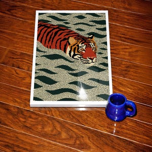 Stylized tiger illustration moving through abstract green wave patterns with dotted textures on a neutral background. The bold orange and black striped tiger contrasts with the rhythmic organic shapes, creating a dynamic maximalist composition. Hand drawn details and modern folk art influences give the artwork a playful yet powerful visual identity. Perfect for living room wall decor, kids room styling, eclectic interiors, or jungle themed spaces seeking a bold statement animal artwork.