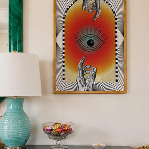 All seeing eye poster featuring a surreal central eye, chrome hands, black-and-white optical lines and a fiery orange gradient in a psychedelic collage style. Display this trippy art print in a living room, bedroom, studio, dorm or eclectic gallery wall to create a bold focal point with graphic movement and retro energy. Designed for collectors of surrealism, optical art and unconventional interiors who enjoy mysterious symbolism, vivid color and artwork that immediately starts a conversation.