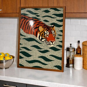 Stylized tiger illustration moving through abstract green wave patterns with dotted textures on a neutral background. The bold orange and black striped tiger contrasts with the rhythmic organic shapes, creating a dynamic maximalist composition. Hand drawn details and modern folk art influences give the artwork a playful yet powerful visual identity. Perfect for living room wall decor, kids room styling, eclectic interiors, or jungle themed spaces seeking a bold statement animal artwork.