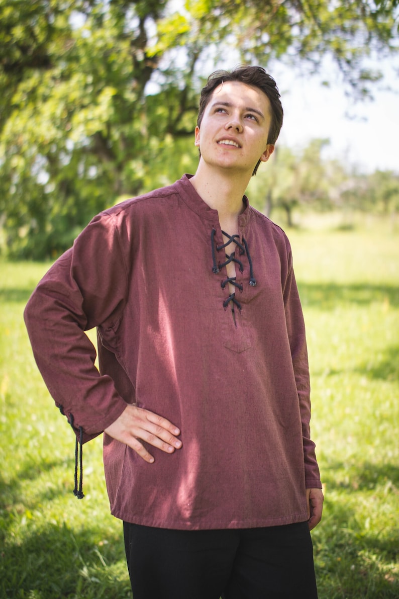 May include: A maroon long-sleeved shirt with a lace-up neckline. The shirt is made of a soft, comfortable fabric and has a relaxed fit.