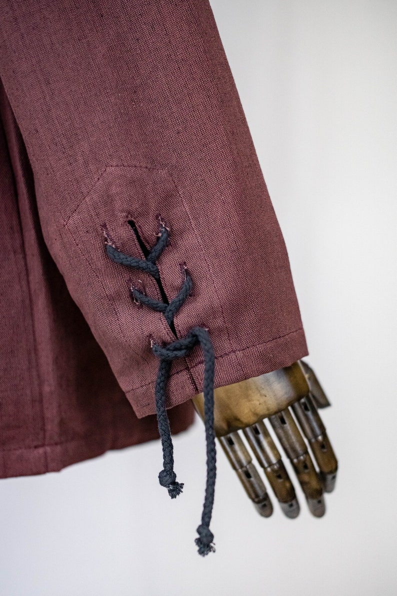May include: A burgundy linen jacket with black lace-up detail on the sleeve cuffs.