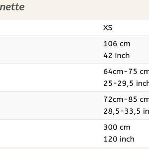 May include: Size chart for Schn&uuml;rrock Modell Annette skirt, with measurements in inches and centimeters. Includes sizes XS, S-M, and L, detailing total length, waist circumference, hip width, and hem width.